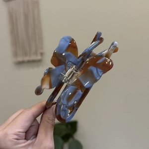 Detailed close-up of butterfly hair claw clip with blue and brown marbled texture