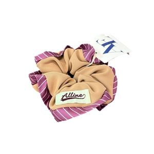 Chouchou en tissu beige et à rayures violettes avec étiquette de marque pour cheveux