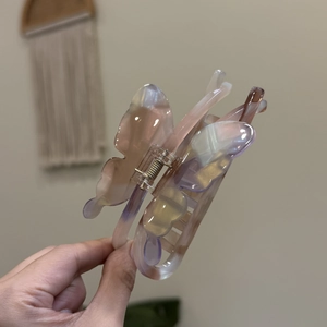 Close-up of a pearlescent acetate butterfly hair claw clip with a pastel marble effect