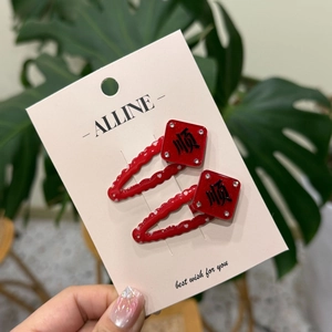 Gros plan de barrettes à cheveux rouges ondulées avec cœurs blancs et motifs de chance