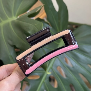 Close-up of a large rectangular hair claw clip with a three-color block wave pattern