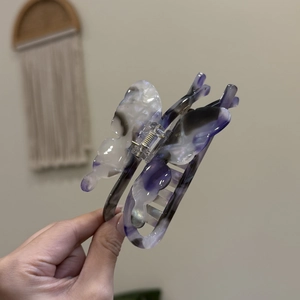 Detailed macro view of butterfly hair claw clip with purple marble acetate texture