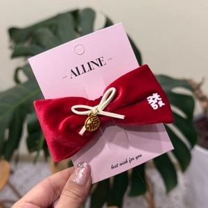 Détail du nœud à cheveux en velours rouge avec pendentif doré Fu et broderie du signe Xi