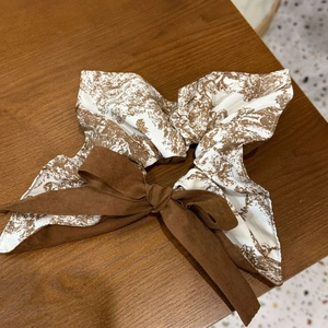 Two-tone bow scrunchie with vintage French toile pattern on dark wood background