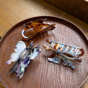 Detailed set of three acetate claw clips with marble textures on a wooden tray