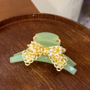 Elegant light green acetate shark hair clip with a stylish lace bowknot on a wooden tray