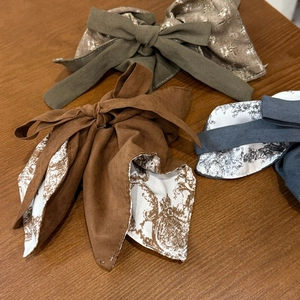 Close-up showing fabric texture of two-tone bow scrunchies with floral patterns
