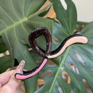 Detail view of a tricolor wave hair claw clip featuring pink and coffee color blocking