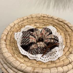 Plaid checkered hair scrunchie with lace edge and bow on a woven straw basket