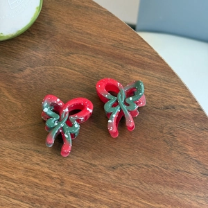 Détail de deux pinces à cheveux nœud rouge et vert avec des taches d'encre blanches