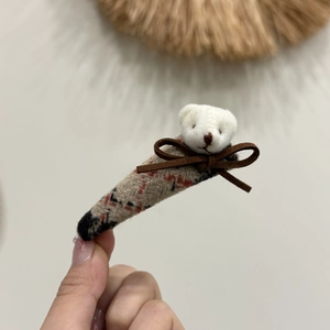 Close-up of cute plush bear with velvet bow on red plaid tweed hair accessory detail