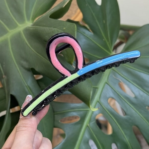Detail view of wavy multicolored shark hair claw clip with glossy black finish