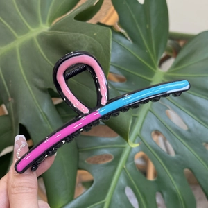 Detailed view of wave-shaped large hair claw clip in pink and blue contrast colors