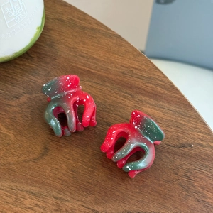 Détail de pinces à cheveux dégradées rouge et vert avec taches blanches sur bois