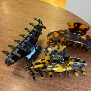 Three-piece set of large tortoise shell and black acetate hair claws on a wood surface
