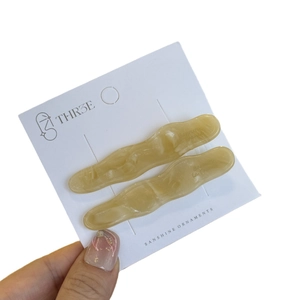 Lot de deux barrettes à cheveux ondulées en acétate jaune crème sur carte de marque