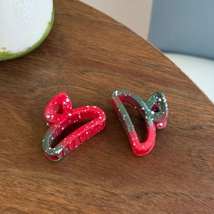 Détail de deux pinces à cheveux en résine avec dégradé rouge et vert et taches d'encre