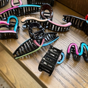 Detail view of colorful oil-dripped heart and wavy patterns on black resin hair claws