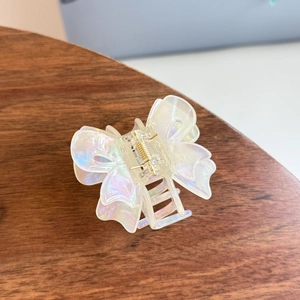 Iridescent butterfly hair claw clip with pearlescent finish on a wooden surface