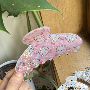Detailed view of pink laser acrylic hair claw clip with cute cat and cherry patterns