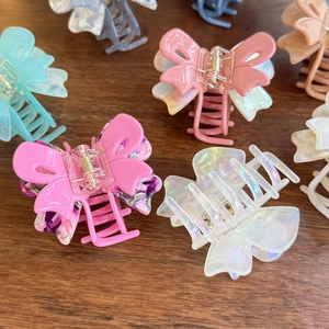 Detailed macro view of acetate butterfly hair claws in multiple colors on a wooden surface