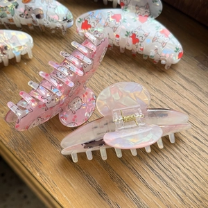 Detail of handmade acrylic cat hair claw clips with iridescent hearts and cherry patterns