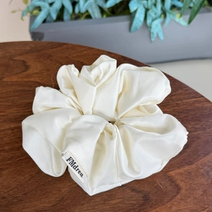 Chouchou élégant en satin crème sur table en bois avec décor de plantes minimalistes