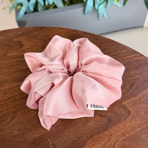 Chouchou élégant en soie rose clair avec design plissé sur support en bois naturel