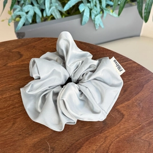Chouchou élégant en satin bleu clair sur table en bois avec plantes vertes décoratives