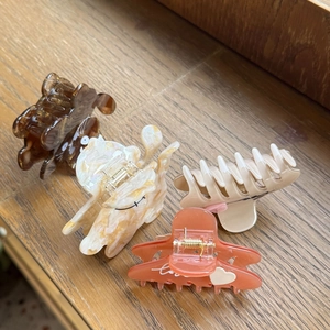 Detail view of acetate claw clips in tortoiseshell and floral patterns with Love text