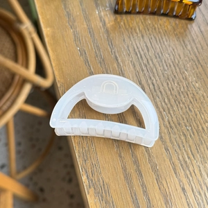 Translucent white hollow semicircular hair claw clip for women on a wooden table