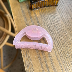 Pink translucent large butterfly hair claw clip with rose gold metal spring on wood