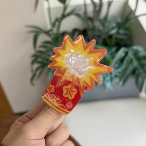Detail view of festive red acrylic hair claw clip with golden floral and cloud patterns