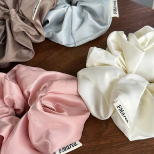 Gros plan de quatre chouchous en satin de soie colorés avec étiquettes sur une table en bois