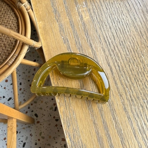 Macro shot of large amber-colored hollow semicircle hair claw clip on wooden desk