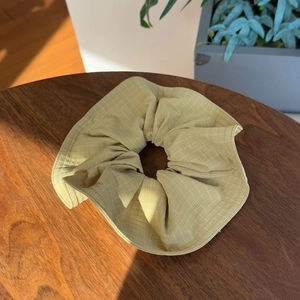 Pale yellow checkered canvas scrunchie on wooden desk with elegant sunlight and shadows