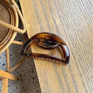 Detail of amber translucent semi-round hair claw clip on a wooden table surface