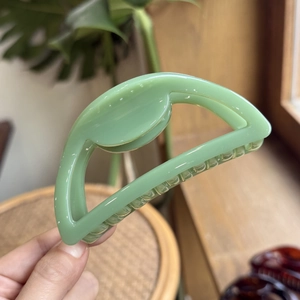 Detail of light green hollow semi-circle hair claw clip with smooth glossy finish