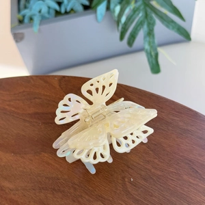 Elegant pearlescent butterfly hair claw clip with multi-layer design on wooden tray