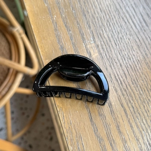 Detail view of a black hollow semicircular shark hair claw clip on a wooden surface