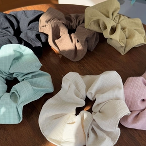 Detailed view of six oversized scrunchies in various colors on a dark wooden surface