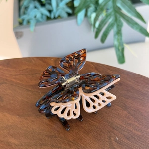 Elegant butterfly claw clip with tortoiseshell pattern and layered wings on a wooden table