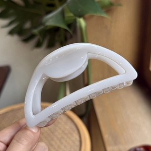 Detail of 10cm cream white hollow semicircular shark hair claw clip held by hand