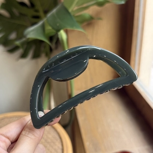 Detailed side view of dark green hollow semi-circular hair claw clip for elegant styling