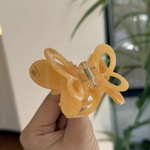 Handgehaltener, bernsteinfarbener Schmetterling-Haarclip mit Marmorstruktur