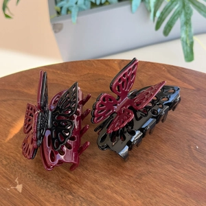 Detail of burgundy and black butterfly hair claws with hollow design and glossy finish