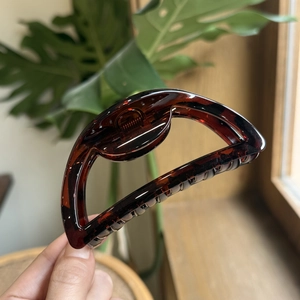 Detail of 10cm amber tortoiseshell claw clip held by hand showing size and resin gloss