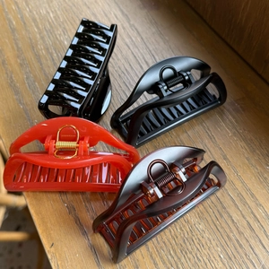 Set of four 10cm claw clips in black and red finishes on a wooden surface