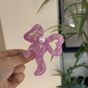 Elegant purple acetate hair claw clip with bow design and large central pearl ornament