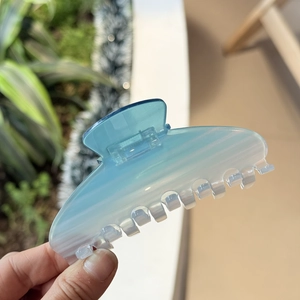 Detail of blue gradient acetate hair claw clip showing glossy finish and 7-tooth design